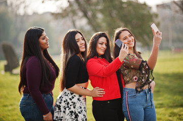 Group of four happy and pretty latino girls from Ecuador posed at street and making selfie on phone.