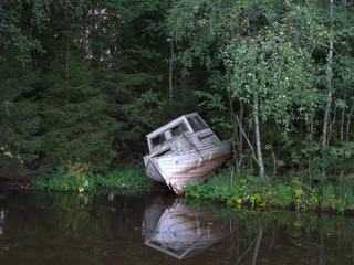 Abandoned old boat in forest by the river