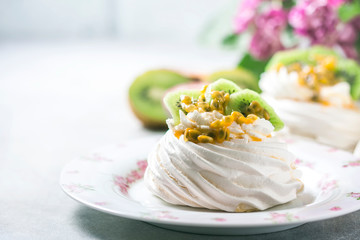 Homemade cake Pavlova with whipped cream, fresh kiwi and passion fruit.