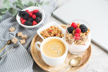 Healthy Breakfast Cup of Coffee Greek Yogurt with Homemade Granola, Berries, Raspberries and Blackberries Work Laptop Morning Concept