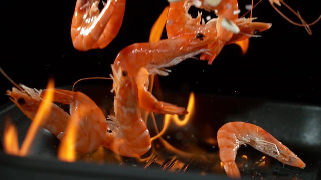 Super slowmotion footage of throwing fresh prawns and seasoning on ignited pan, 1000fps 4k