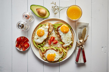 Delicious healthy breakfast with sliced avocado sandwiches with fried egg on top of bread. With...