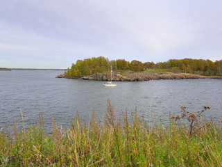 Small sailing boat between islands on calm sea