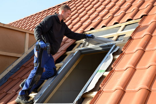 Dachdecker baut Dachfenster von "Velux" auf dem Bau in rote Dachziegel D&auml;cher ein