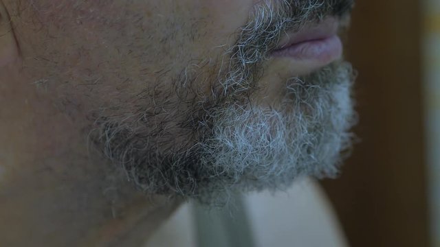 A Elderly Man Cuts His Beard With Scissors