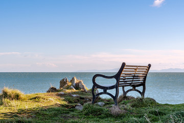 An empty bench overlooking the sea late in the afternoon