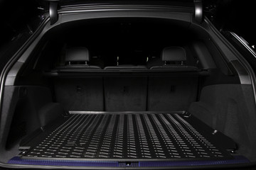The big black empty trunk of SUV car with rubber mat and with leather folder on the floor  Open...