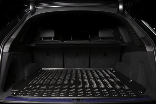 The big black empty trunk of SUV car with rubber mat and with leather folder on the floor  Open luggage carrier of car closeup