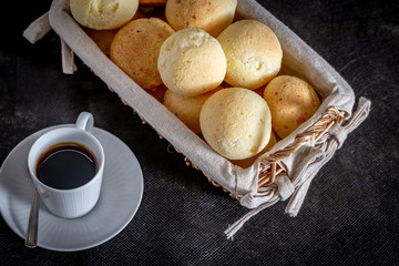Brazilian homemade cheese bread, AKA 'pao de queijo' in a rustic basket and a cup of coffee