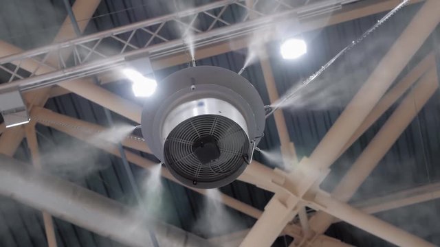 An industrial humidifier sprays water particles around itself at the ceiling of an industrial plant. Shot in motion
