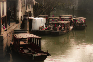 Fototapeta na wymiar Boats with roof top on canal river running through Pinjiang Historic Quarters in the old town of Suzhou, China