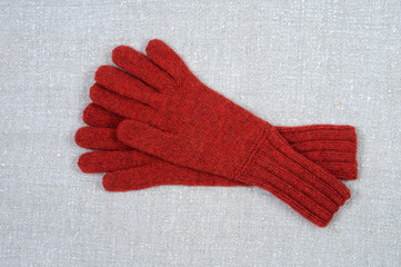 Red handmade gloves on the background of the fabric. View from above.