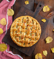 baked whole round apple pie on a brown wooden board