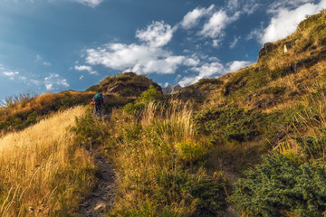 Hiker with backpack going up in the mountains
