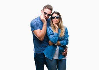 Young couple in love wearing sunglasses over isolated background thinking looking tired and bored with depression problems with crossed arms.