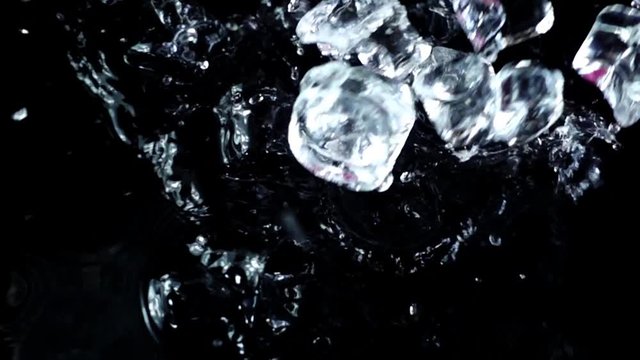 Falling of cubes of ice on a black background. Slow motion.