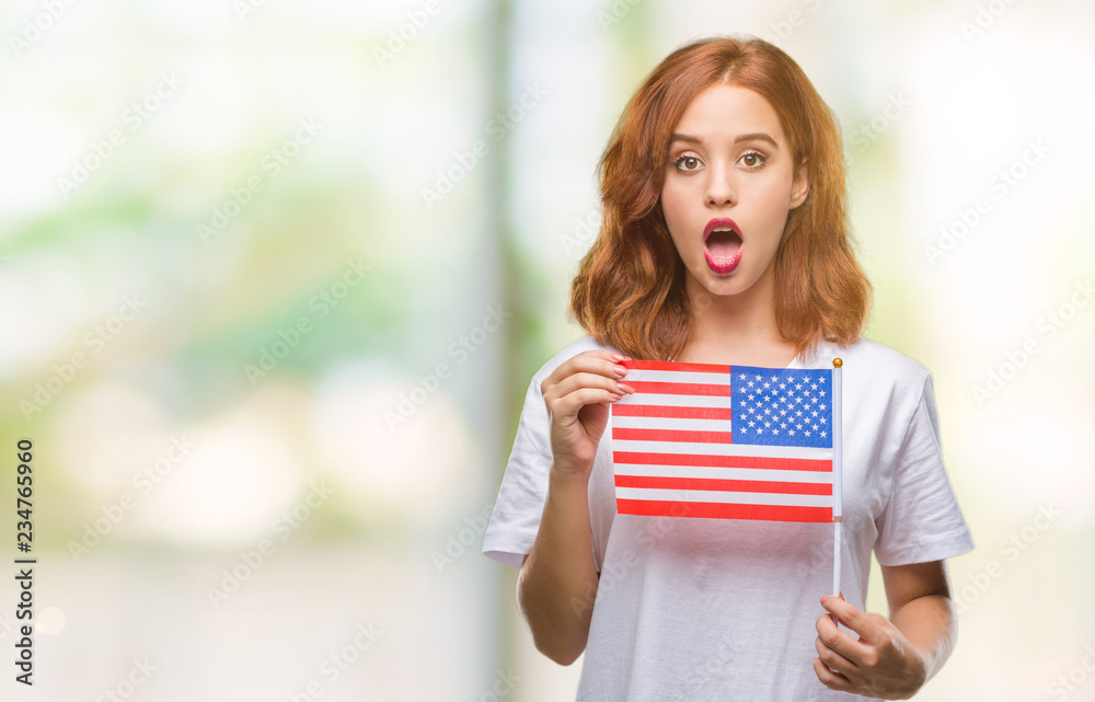 Poster young beautiful woman holding flag of america over isolated background scared in shock with a surpri