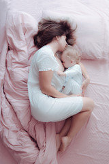 Young mother is breastfeeding a baby lying in bed