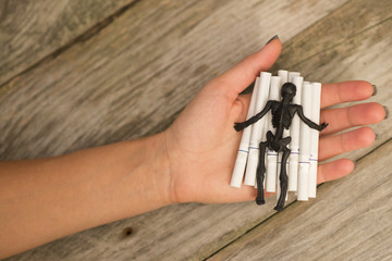 Black skeleton standing on many cigarettes on smoker hand, smoking kills concept