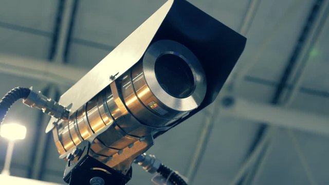 Metallic security camera is checking the surrounding area in search of the offender. Shot in motion