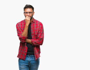 Adult hispanic man wearing glasses over isolated background looking stressed and nervous with hands on mouth biting nails. Anxiety problem.