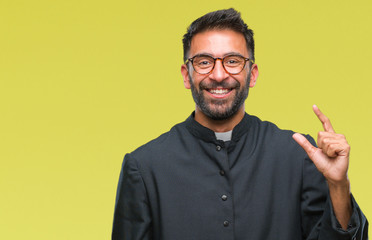 Adult hispanic catholic priest man over isolated background smiling and confident gesturing with hand doing size sign with fingers while looking and the camera. Measure concept.