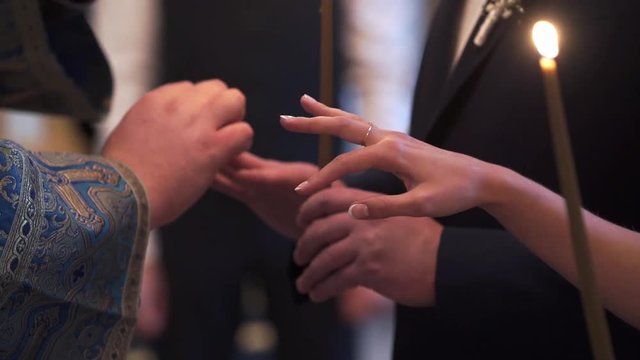 Priest praying in church at wedding ceremony and put on rings for newlyweds bride and groom