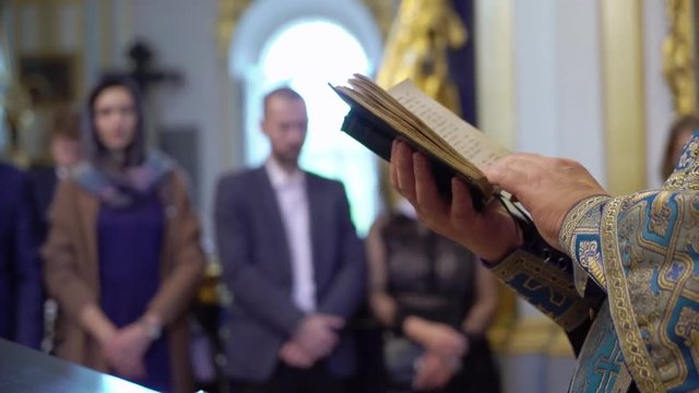 Priest praying with Bible book in church at ceremony