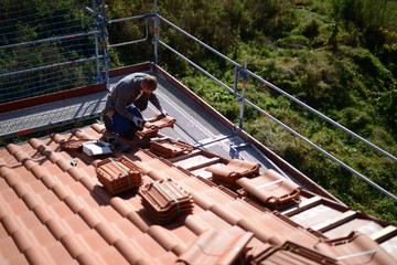 Dachdecker bei der Arbeit gesichert durch ein Bau Gerüst als Arbeitsschutz