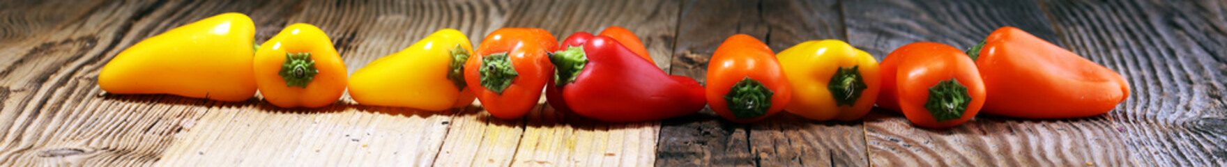 Fresh red, yellow and orange bell pepper on wooden background. raw vegetable.