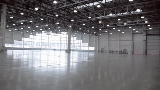 Huge, spacious hangar with large windows, lit by lots of lamps
