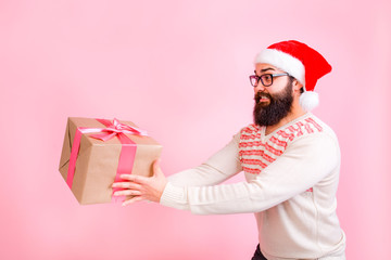 Happy bearded man in Santa Claus hat gives gift box