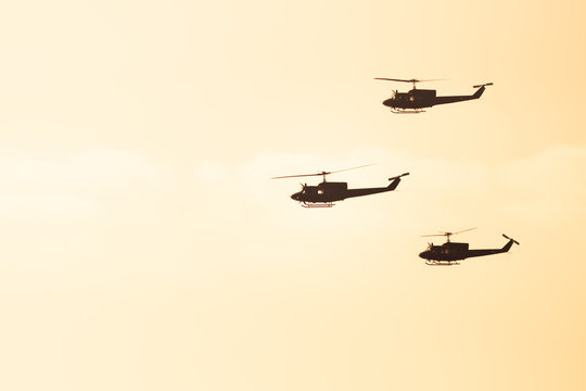 three helicopters flying against sunlight background