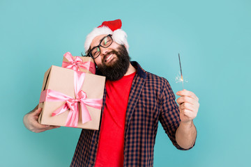 Obraz premium Happy man in Santa Claus hat with Christmas gifts clutching to himself