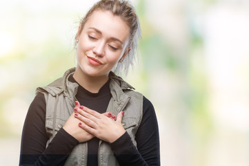 Young blonde woman over isolated background smiling with hands on chest with closed eyes and grateful gesture on face. Health concept.