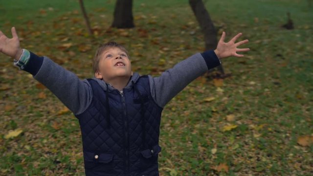Young boy spinning with hands spread up high