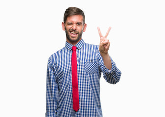 Young handsome business man over isolated background smiling with happy face winking at the camera doing victory sign. Number two.