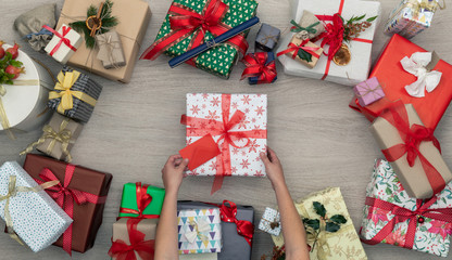 Obraz premium Hands with gift present box in vertical top view wooden table full of christmas or birthday gifts presents.Xmas winter holiday season party social media card background,portrait story