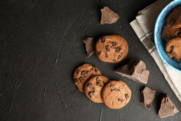 Tasty chocolate chip cookies on dark background, flat lay. Space for text