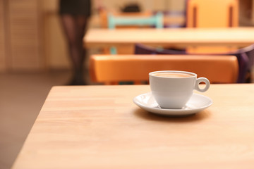 Cup of fresh aromatic coffee on table against blurred background. Space for text