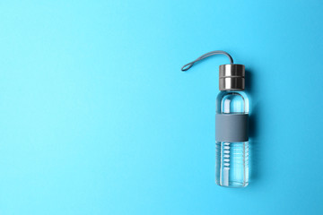 Sport bottle with space for text on color background, top view