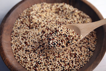 Spoon with mixed quinoa seeds over plate, closeup