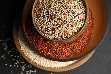 Composition with different types of quinoa on black background, top view