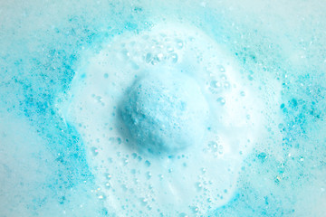 Color bath bomb dissolving in water, top view