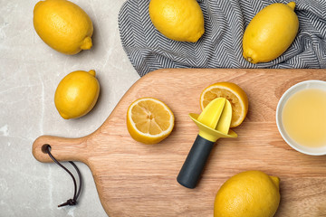 Flat lay composition with fresh lemons and plastic squeezer on table