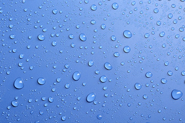 Water drops on color background, top view