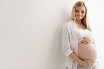 Portrait of beautiful pregnant woman on light background. Space for text