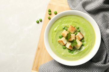 Flat lay composition with fresh vegetable detox soup made of green peas in dish and space for text on table