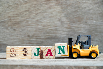 Toy forklift hold block N to complete word 23jan on wood background (Concept for calendar date in 23 month January)