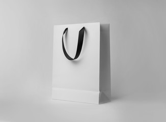 Paper shopping bag with ribbon handles on white background. Mockup for design